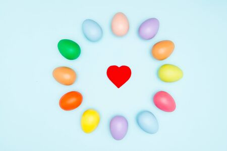 Colorful easter eggs around the heart shape on pastel backgroundの写真素材