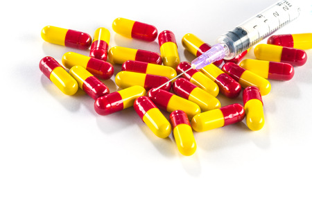 Yellow with red capsules and syringe, medication cure close upの写真素材