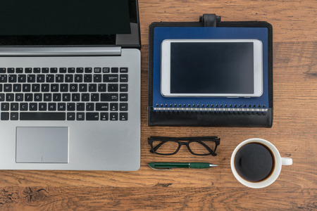 Laptop Tablet notebook and pen with a cup of coffee on the deskの写真素材