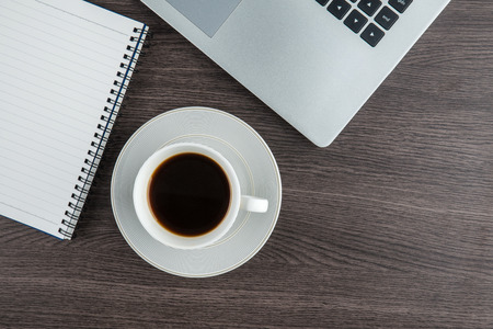 Laptop, notebook and pen with coffee cup on work deskの写真素材