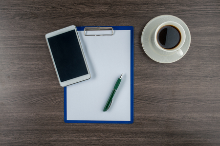 Tablet, paper and pen with a cup of coffee on work deskの写真素材