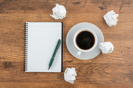 crumple paper, notebook and pen with cup of coffee on the deskの写真素材