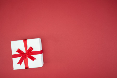 luxury color gift box for holiday event with beautiful silk wrap on red background isolatedの写真素材