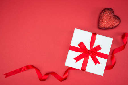 gift box wrap silk ribbon with love heart shape on red backgroundの写真素材