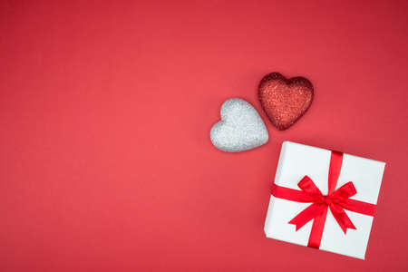 gift box wrap silk ribbon with love heart shape on red backgroundの写真素材