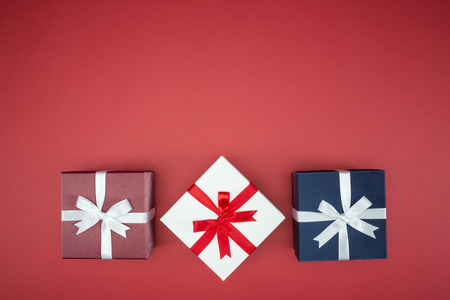 luxury color gift box for holiday event with beautiful silk wrap on red background isolatedの写真素材