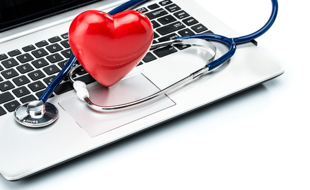 Cardiologist, heart disease research, stethoscope and heart shape on laptop keyboardの写真素材