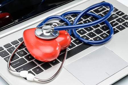 Cardiologist, heart disease research, stethoscope and heart shape on laptop keyboardの写真素材
