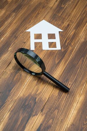 paper house with Magnifying Glass, House hunting on wooden background