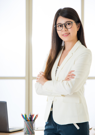 Asian attractive businesswoman arms crossed and smiling standing in officeの写真素材