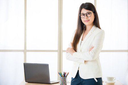 Asian attractive businesswoman arms crossed and smiling standing in officeの写真素材