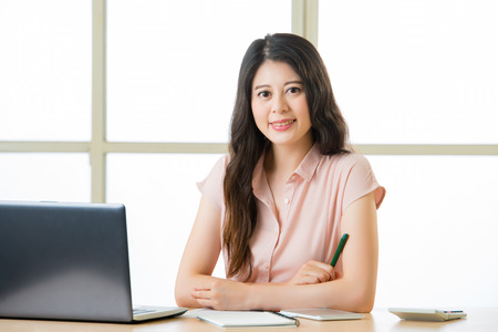 Young Asia businesswoman sitting and smiling at working deskの写真素材