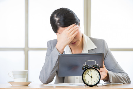 Young asian businesswoman worried about time in officeの写真素材
