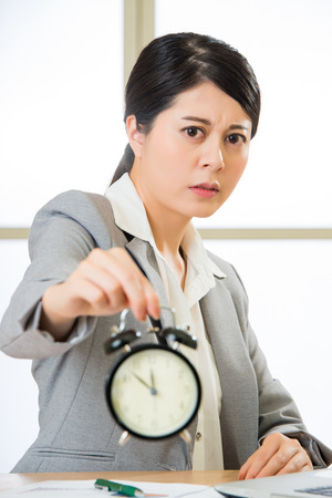 Asian businesswoman holding  alarm clock in officeの写真素材
