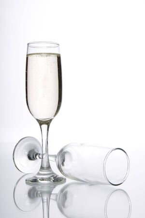 Glass of champagne and empty champagne glass on white backgroundの写真素材