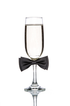 Glass of champagne with black bow tie on white backgroundの写真素材