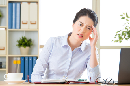 Young asian business woman with headache in officeの写真素材