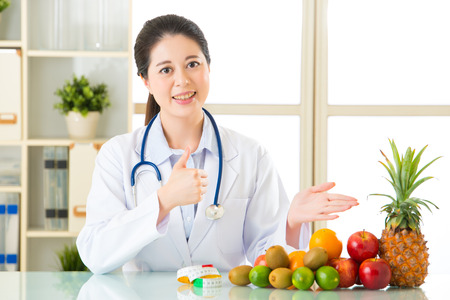 Young asian nutritionist recommend eating fruits and thumbs up, healthy eatingの写真素材