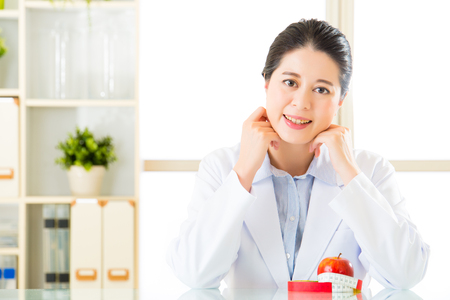 Young asian nutritionist doctor measuring an apple, diet planの写真素材
