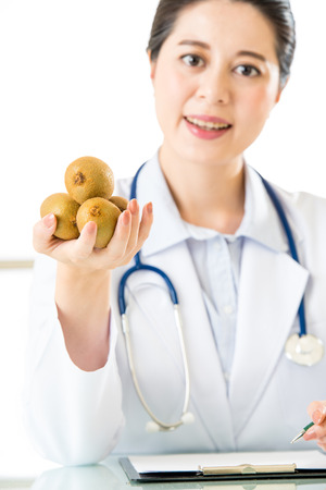 Young asian nutritionist doctor writing diet plan, kiwiの写真素材