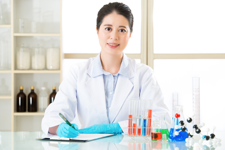 Asian female scientist recording research data with smile face in laboratoryの写真素材