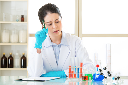 Asian female scientist distressed to recording her research data on clipboard in laboratoryの写真素材
