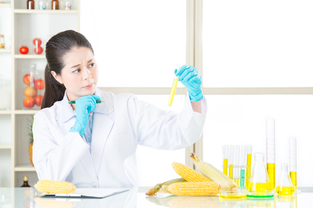 Asian female scientist holding an corn and recording the data on clipboardの写真素材