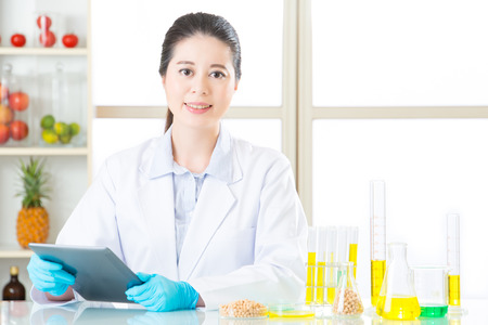 Asian female scientist touch the digital tablet holding soya bean in laboratoryの写真素材