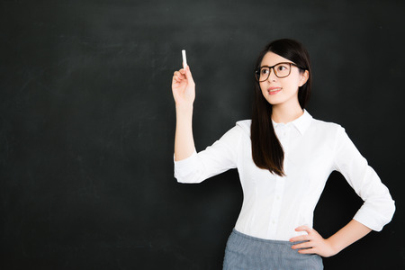 A good asian teacher teach on blackboard with chalk in classroom