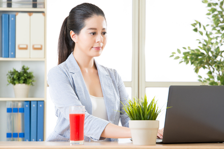 asian business woman using computer and drinking fresh watermelon juiceの写真素材