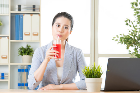 asian business woman enjoy to drinking fresh watermelon juice in officeの写真素材
