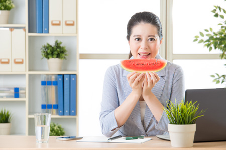business woman in professional suit eating sweet summer watermelonの写真素材