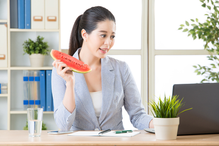asian business woman having fresh watermelon and using computer for summer projectの写真素材
