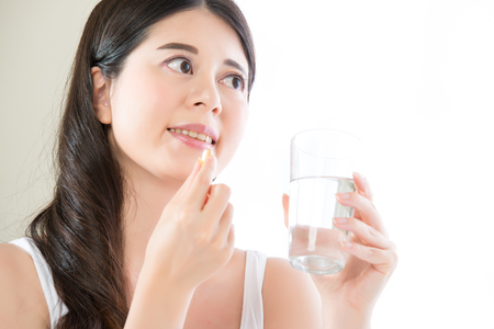 beautiful asian women eating nutritional fish oil supplement for healthy diet at homeの写真素材