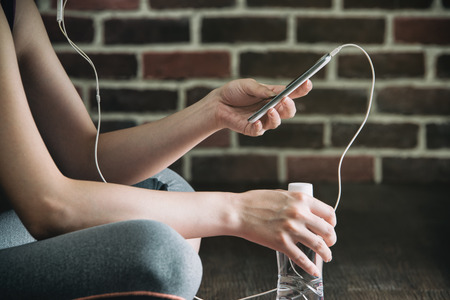 enjoy listen to music drinking water after fitness exercise training, sitting on wooden floor,...