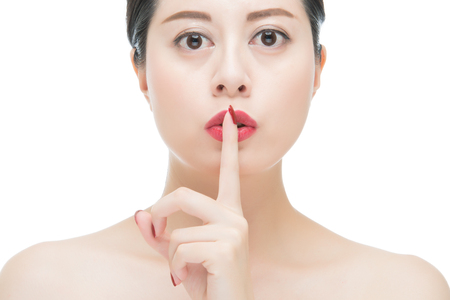 beauty asian woman red lips with red lipstick and finger showing hush silence sign, isolated on white backgroundの写真素材