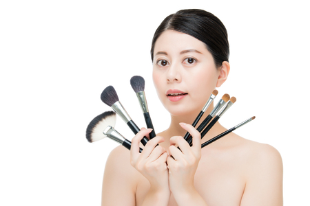 portrait of beauty asian smiling woman brunette holding brushes for makeup. isolated on white backgroundの写真素材