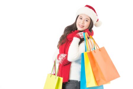 Christmas shopping woman holding shopping bags with gifts. Happy and smiling wearing red santa hat isolated on white background. Mixed race Chinese Asian female model.の写真素材