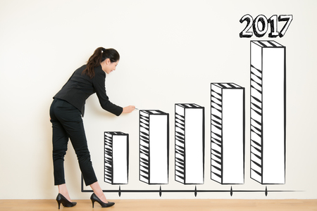 business woman drawing over target achievement graph on white wall background. Concept of scientific approach to business. beautiful mixed race asian chinese with business conceptの写真素材