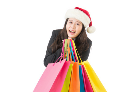 business Woman shopping for christmas gifts. Young asian chinese girl smiling with shopping bags and santa hat. Copy space on the side.の写真素材