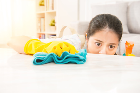 woman cleaning table carefully at home in the living room. mixed race asian chinese model.