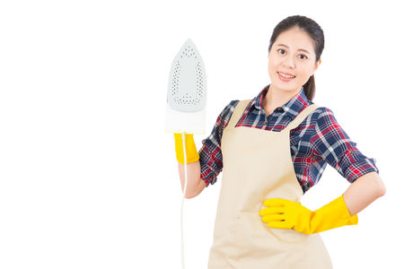 Young smiling woman is ironing with a steam iron on isolated white background. Beautiful fresh energetic multiracial Chinese Asian female model.の写真素材