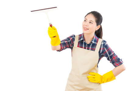 Happy woman in gloves cleaning window with glass wiper at home. Large window glass in foam isolated white background. Beautiful fresh energetic multiracial Chinese Asian female model.の写真素材