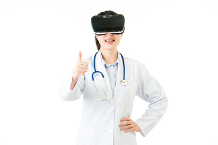 asian female doctor show thumb up by virtual reality. VR headset glasses device. white isolated background. medical and health conceptの写真素材