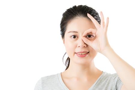 beautiful asian woman show ok gesture for good eye vision. isolated on white background. medical and health conceptの写真素材