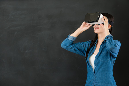 asian woman student enjoy experience virtual reality education. VR headset glasses device. blackboard background. school and education conceptの写真素材