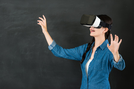 asian woman student control screen with virtual reality. VR headset glasses device. blackboard background. school and education conceptの写真素材