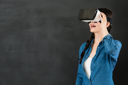 asian woman student enjoy experience virtual reality education. VR headset glasses device. blackboard background. school and education conceptの写真素材