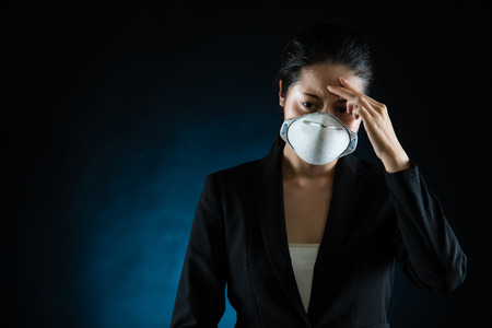 headache business woman feel unwell wearing a face mask to protect health lung virus or pollution. mixed race asian chinese modelの写真素材