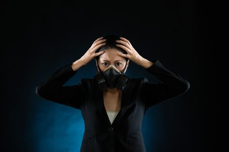 woman in protective mask on black and blue background . Atmosphere pollution factory smog influence on people health concept. mixed race asian chinese modelの写真素材